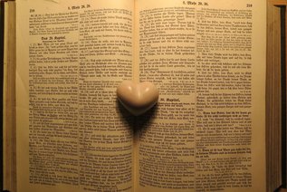 Bibel aufgeschlagen, darauf liegt ein Herz aus Schmeichelstein